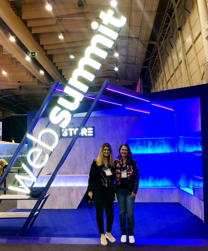 Equipe HUNTINGTI em stand azul escrito em branco "WebSummit"