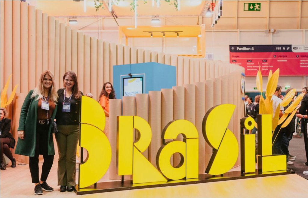 Equipe da HUNGTING TI em evento posando ao lado de uma placa escrita "Brasil"